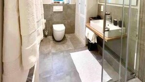 A modern bathroom with a glass shower enclosure, a toilet, and a sink. - Im Herzen der Stadt - EG Wohnung (Paderborn)