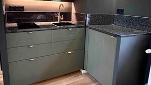 Una cocina moderna con armarios oscuros, encimera de granito y suelo de madera.