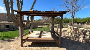 A wooden pergola with two cushioned benches, set against a stone wall and a clear blue sky. - Cream Homes Son Celles Etv3533, Casa de Campo Recién Reformada (Sancellas)