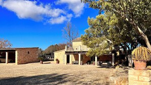 A courtyard with stone flooring, a building with a balcony, and a cactus plant. - Cream Homes Son Celles Etv3533, Casa de Campo Recién Reformada (Sancellas)