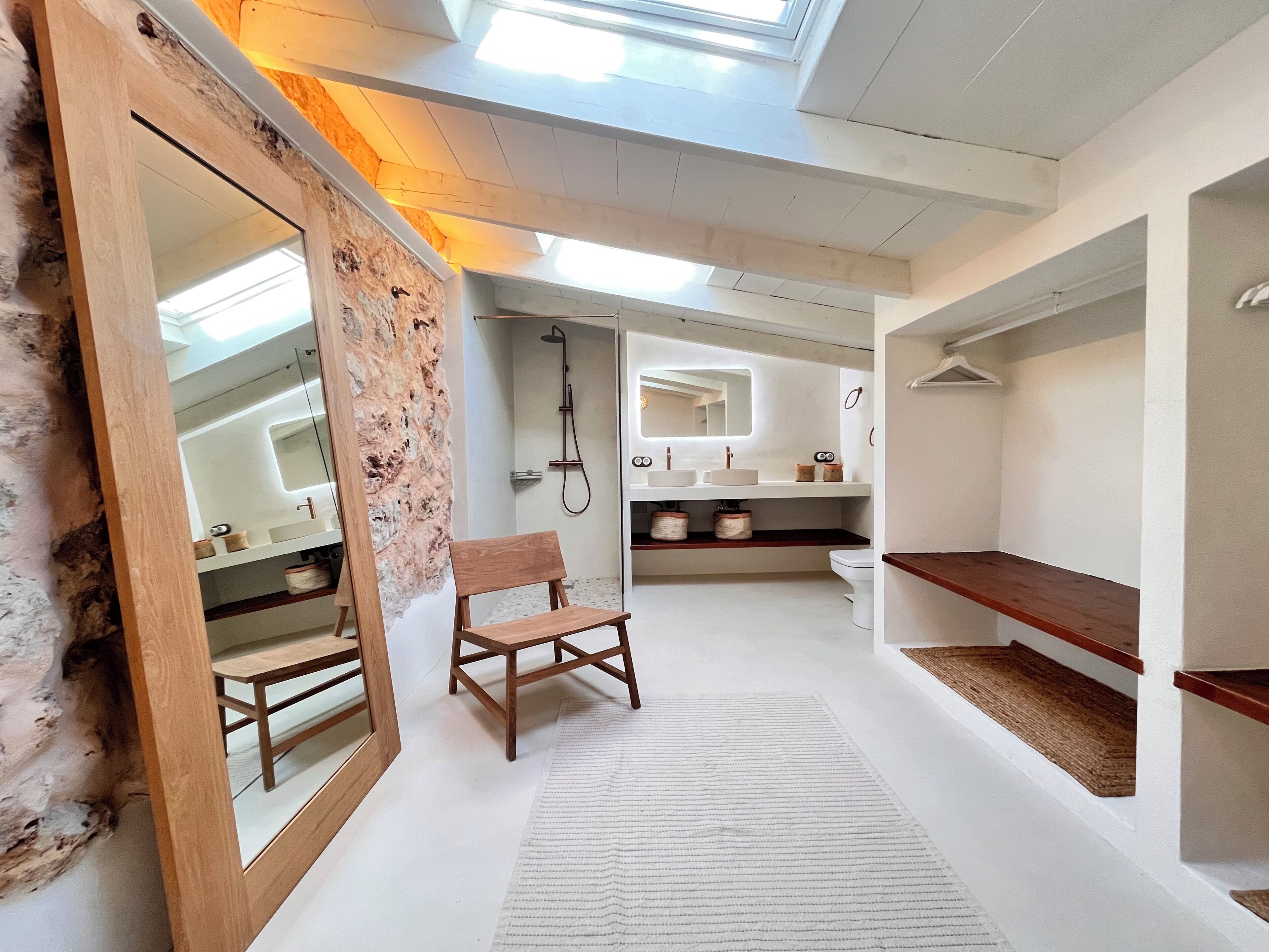 A modern bathroom with a skylight, wooden vanity, and a shower.