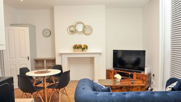 A modern living room with a TV, sofa, and dining area.