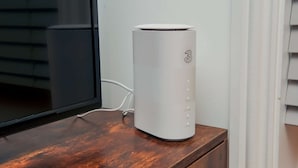 A white device on a wooden surface with a window behind it.