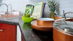A kitchen counter with copper cookware, a green bowl, a cookbook, and a pineapple. - The Pavilion by Select SA (Windsor)