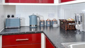 A kitchen with red cabinets, a blue kettle, and a wicker basket on the counter. - The Pavilion by Select SA (Windsor)