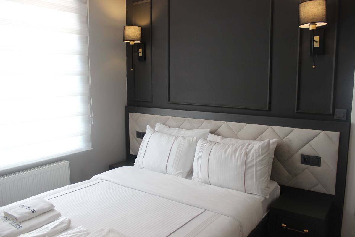 A hotel room with a large bed, two bedside tables, and wall-mounted lamps.
