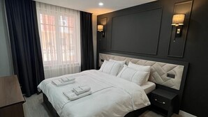 A modern hotel room with a large bed, dark walls, and a wooden floor. - Cosy Suite Hotel (Konyaalti)