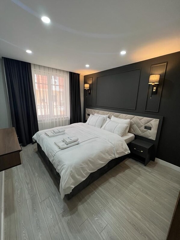 A modern hotel room with a large bed, dark walls, and a wooden floor. - Cosy Suite Hotel (Konyaalti)