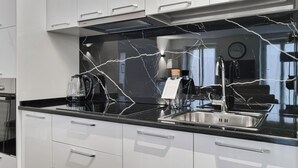Una cocina moderna con armarios blancos, un salpicadero de mármol negro y electrodomésticos de acero inoxidable.