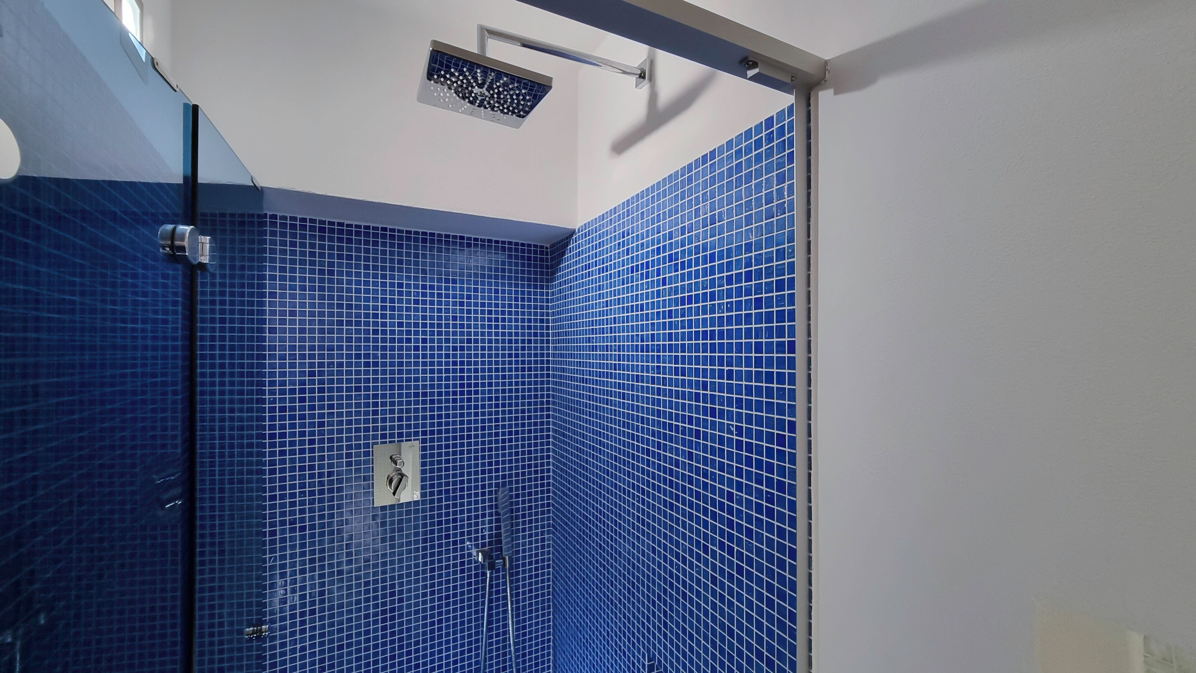 Ein Badezimmer mit blauen Fliesen und einer Duschkabine.