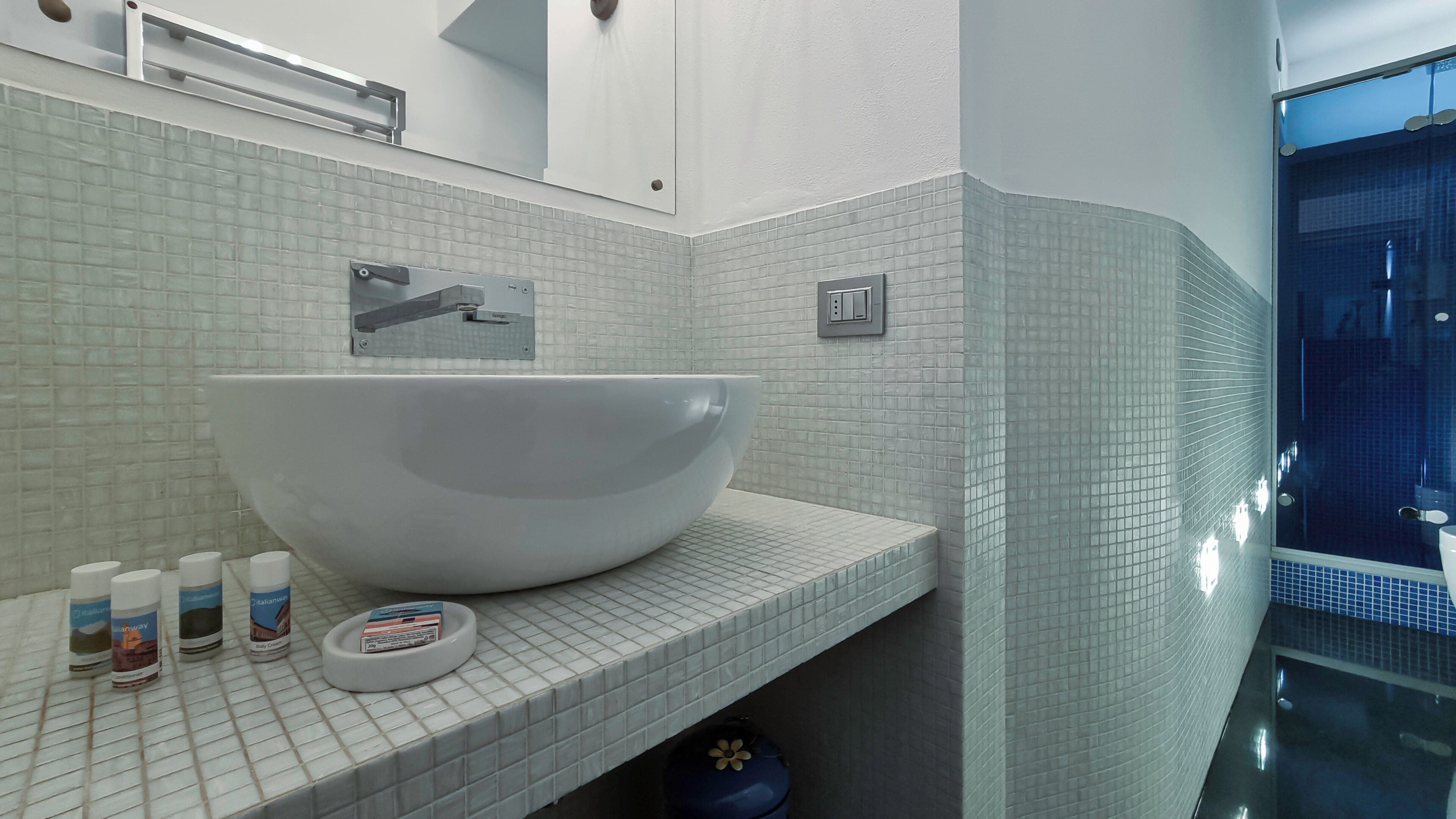 A bathroom with a large white vessel sink, a mirror, and a tiled backsplash.