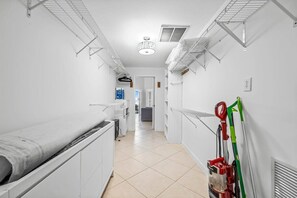 Un couloir propre et blanc, avec un radiateur, un ventilateur de plafond et une serpillière appuyée contre le mur.