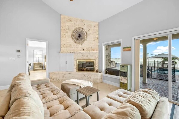 A spacious living room with a fireplace, a large window, and a view of the outdoors.