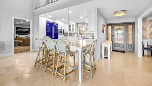 Una cocina amplia con armarios blancos, un refrigerador azul y un comedor con sillas de mimbre.