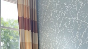 A small sofa with two pillows against a wall with a tree branch pattern.