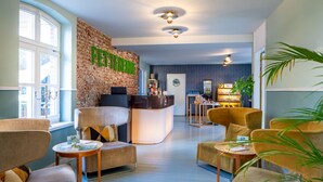 A modern hotel lobby with a reception desk, seating area, and a brick accent wall.