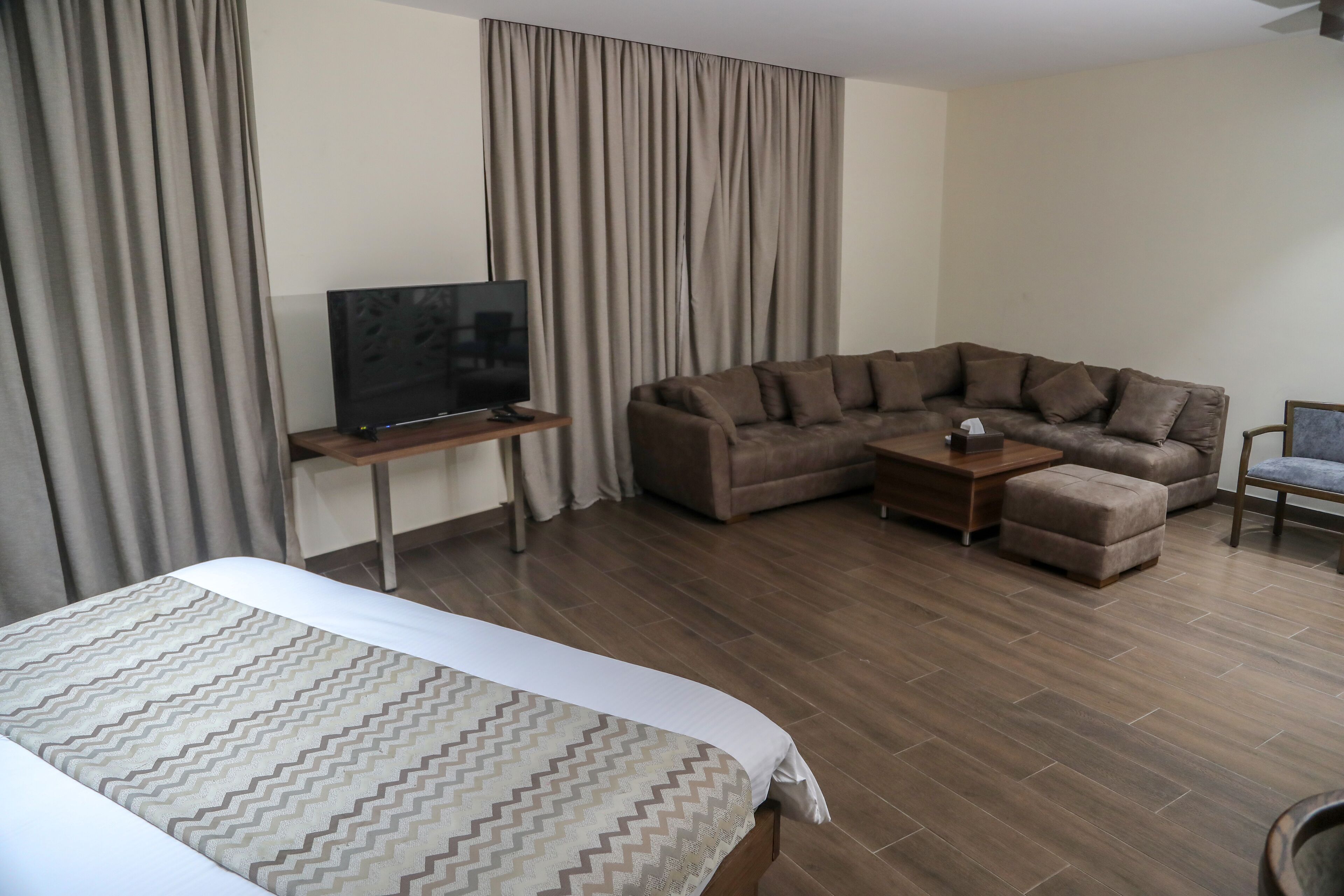 Une chambre d’hôtel avec un lit, un canapé, une télévision et une petite table.