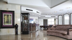A spacious lobby with a large, plush sofa, a decorative vase, and a framed artwork on the wall. - Eden Hotel (Jdeideh)