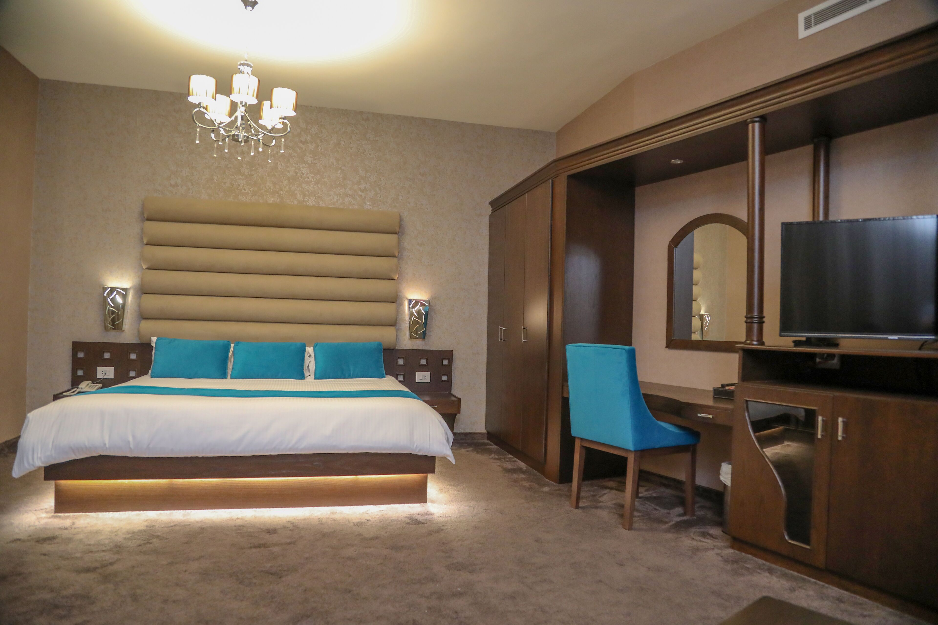 Une chambre d’hôtel avec un grand lit, une télévision, un bureau avec une chaise et une armoire.