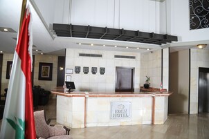 Zona de recepción de un hotel con un mostrador de mármol, un escritorio para la recepción y una puerta grande.