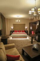 Una habitación de hotel con una cama grande, una araña, un escritorio y un sofá.