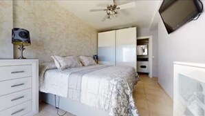 A bedroom with a bed, a TV mounted on the wall, a ceiling fan, and a wardrobe. - Heart of Mojacar Playa with Beautiful " see view " and Sunshine (Ventanicas-el Cantal)