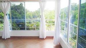 A room with large windows, wooden flooring, and white curtains.