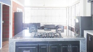 A kitchen with a marble island, black cabinets, and a gas stove.