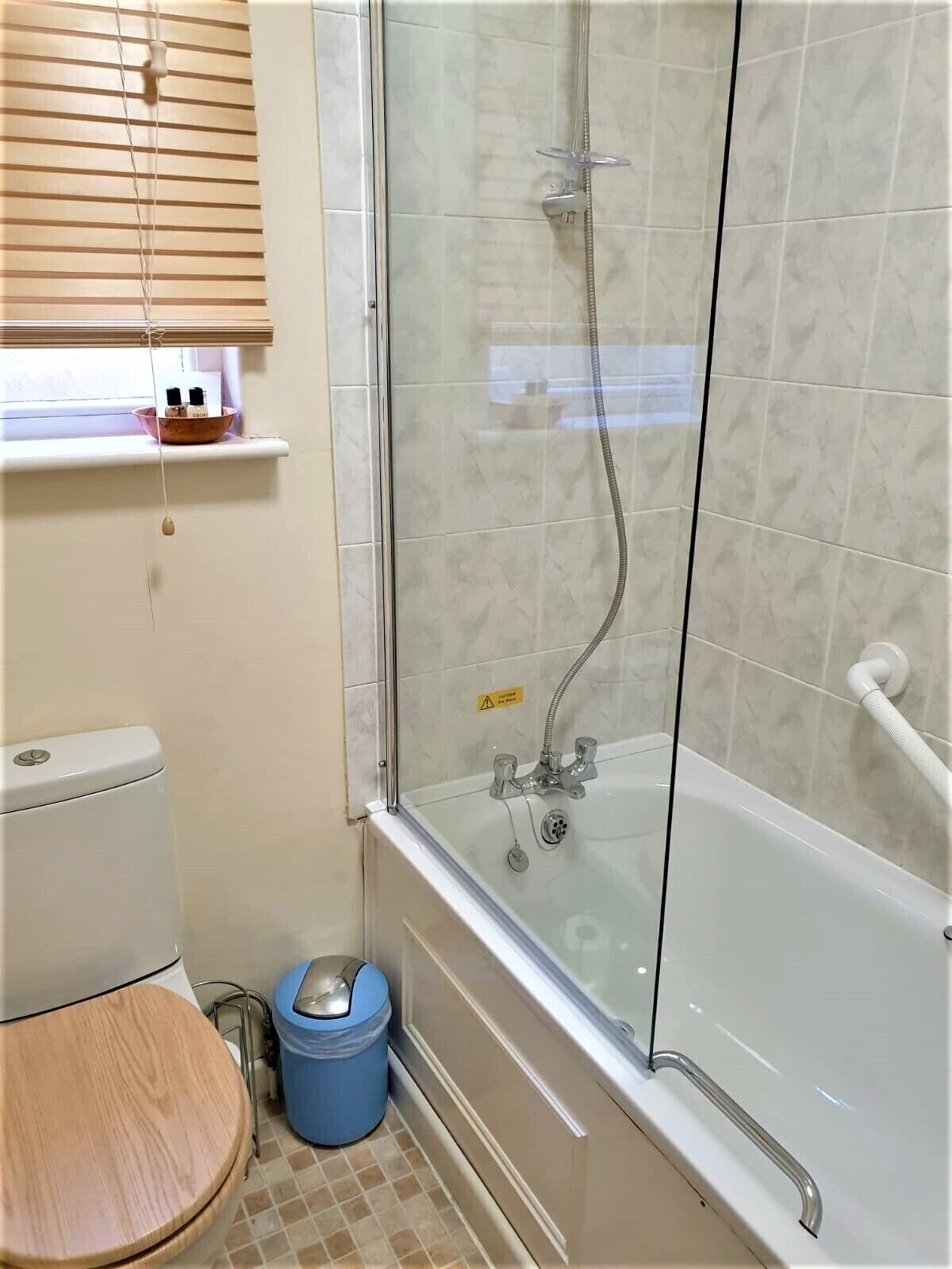 Ein Badezimmer mit Duschkabine, Toilette und blauem Mülleimer.