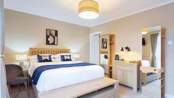 A hotel room with a bed, bedside table, chair, and a mirror.
