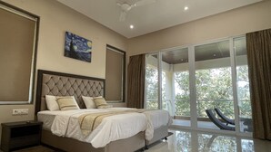 A modern bedroom with a large bed, a ceiling fan, and a view of the outdoors through a sliding glass door.