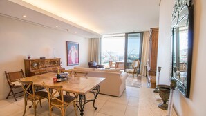 A spacious living room with a dining area, large windows, and a view of the cityscape.