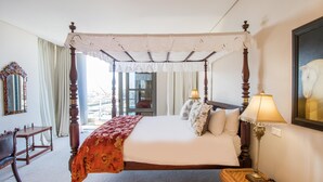 A four-poster bed with a canopy, a bedside table with a lamp, and a mirror on the wall.