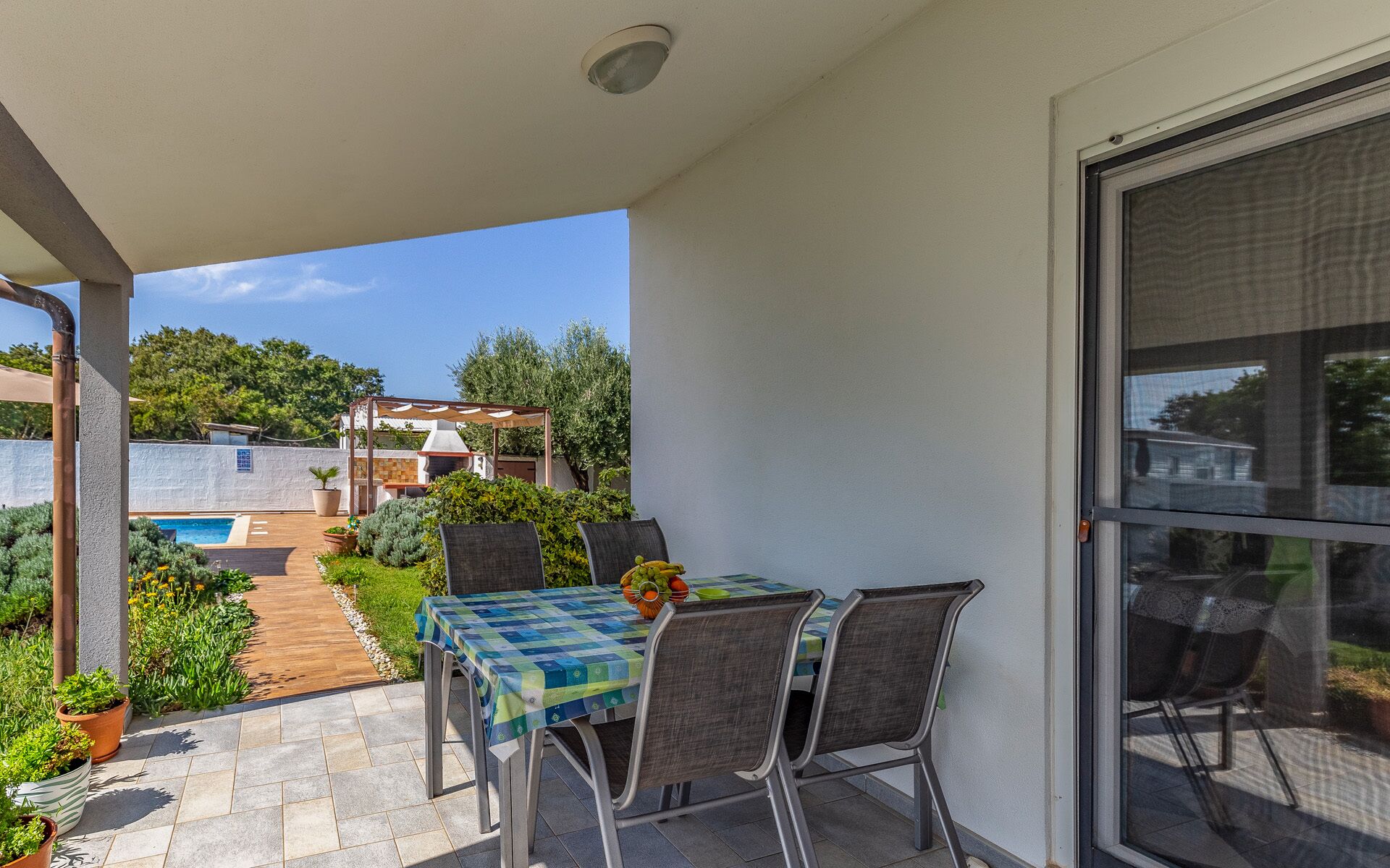 A patio with a table and chairs, a pool, and a garden.