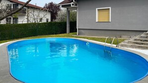 Una piscina blava i nítida amb una escala metàl·lica, envoltada per un paviment de pedra i un bord a l'estil trencadissa.