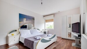 Un dormitori modern amb llit, taules de nit, un televisor i un quadre a la paret.