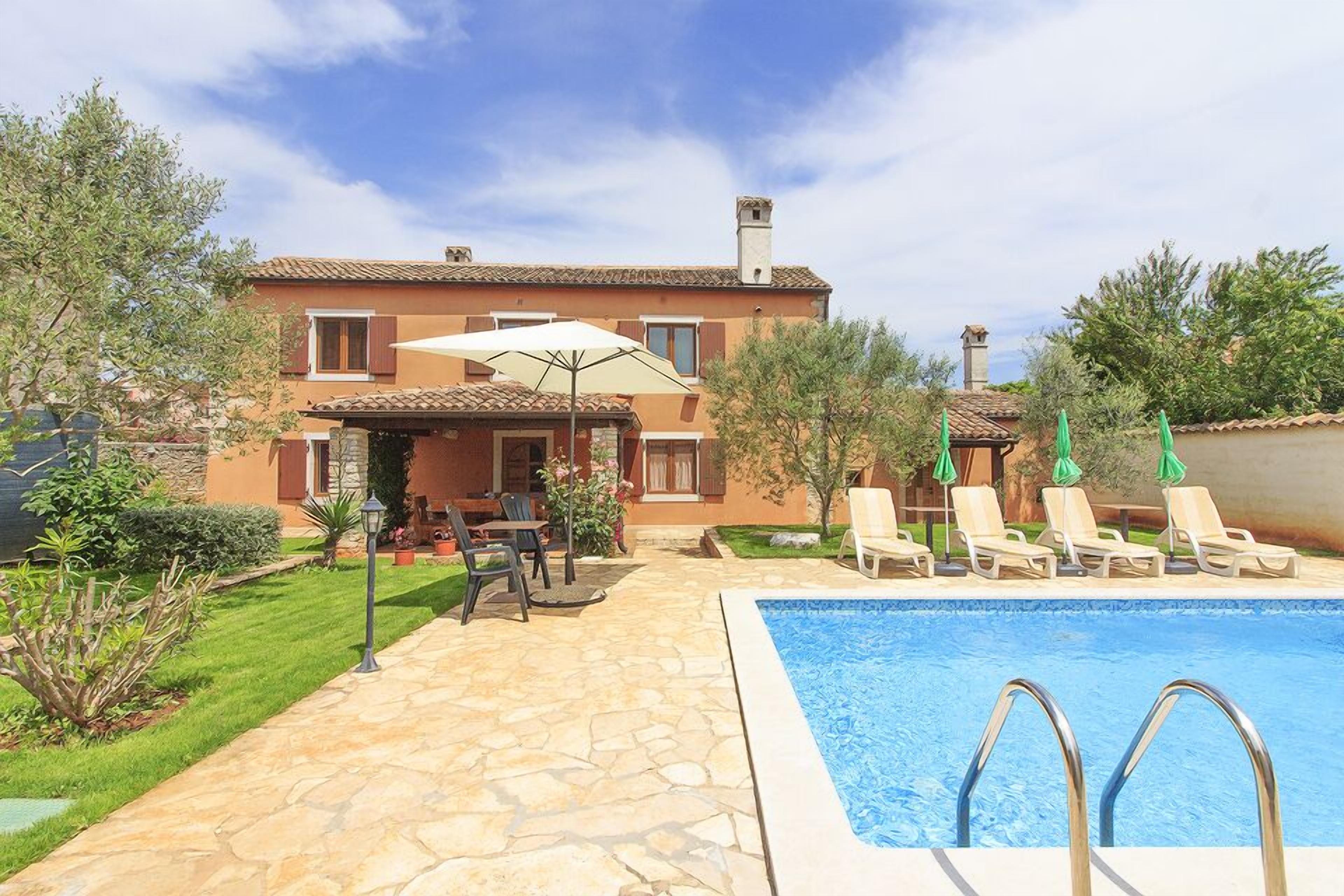 A two-story house with a swimming pool, outdoor seating, and a garden.