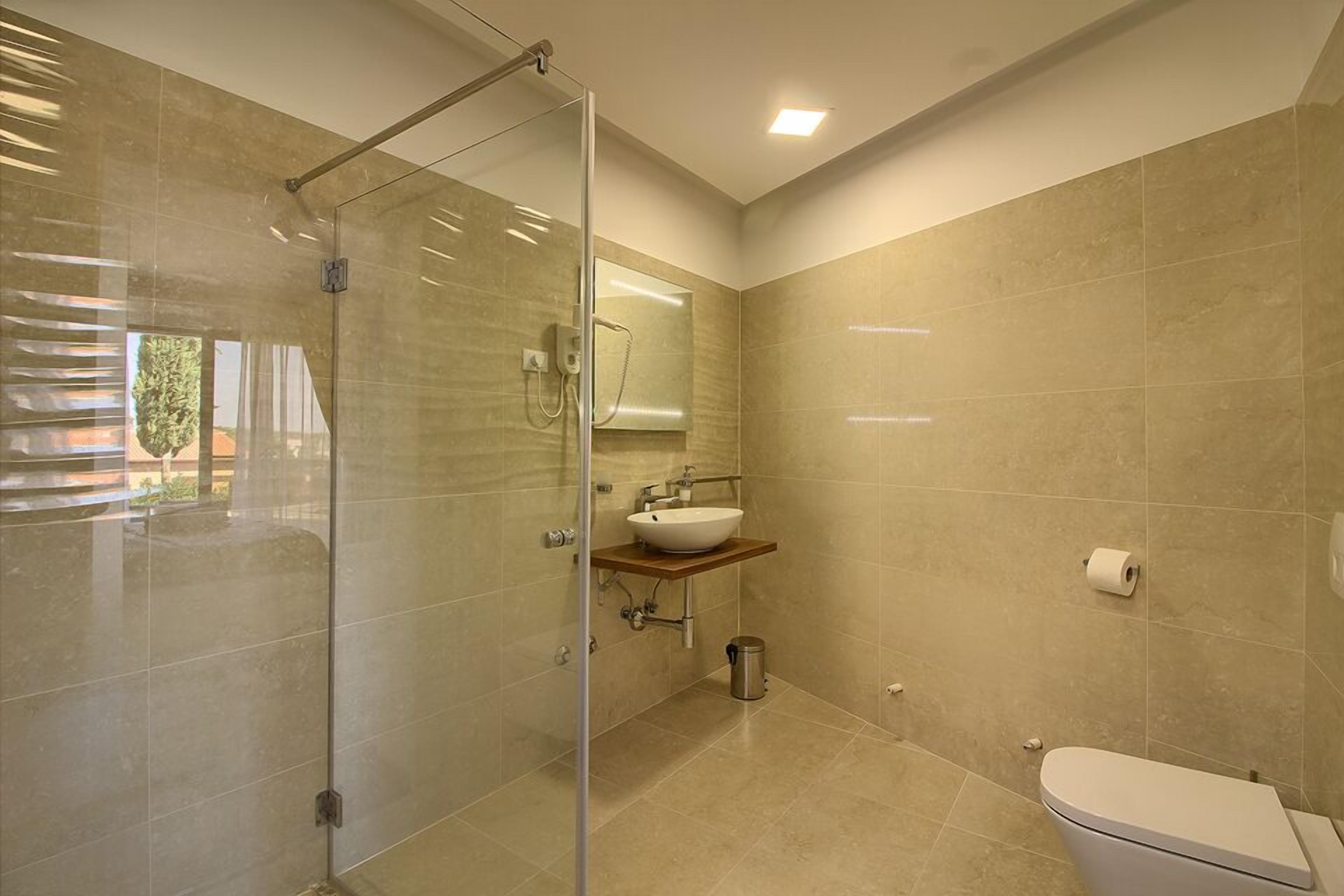 A modern bathroom with a glass shower enclosure, a sink with a mirror, and a toilet.