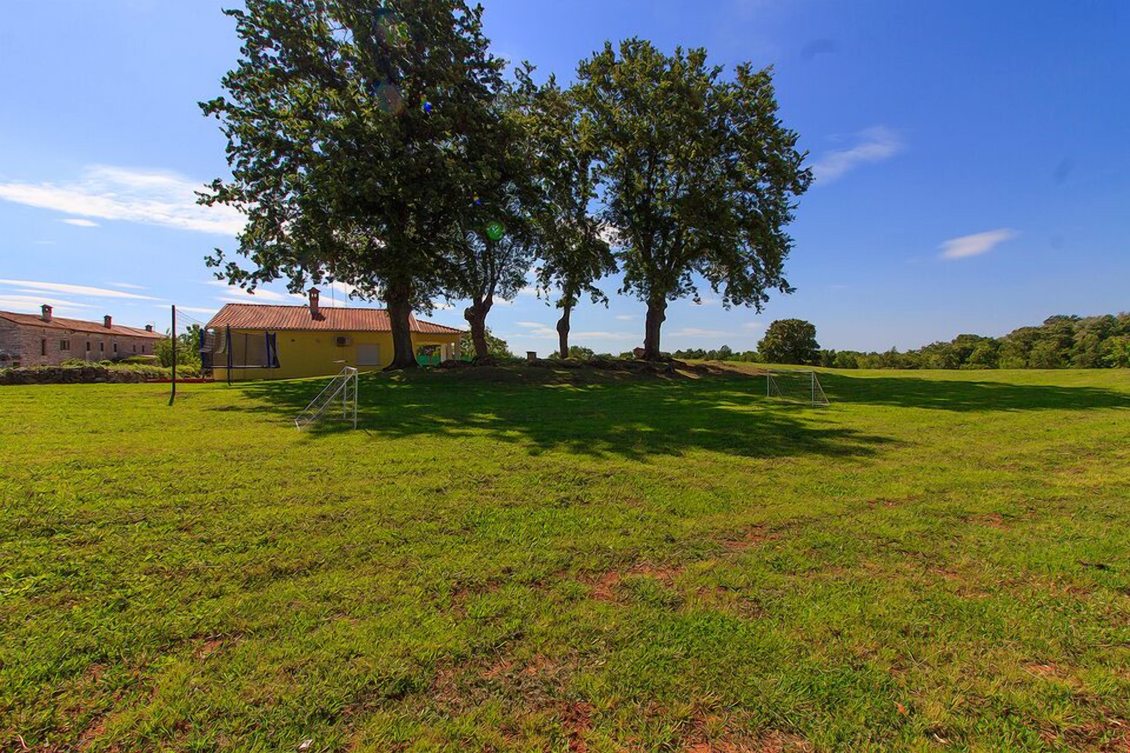 A grassy field with a yellow building and trees.