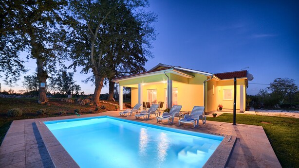 Un espace aménagé au bord de la piscine, comprenant une piscine, des chaises longues et un bâtiment doté d’un patio couvert.