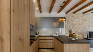 Een moderne keuken met houten kastjes, een accentmuur van steen en een fruitschaal op het aanrecht.