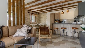 Een moderne woonkamer met een bank, een eethoek en een keuken met barstoelen.