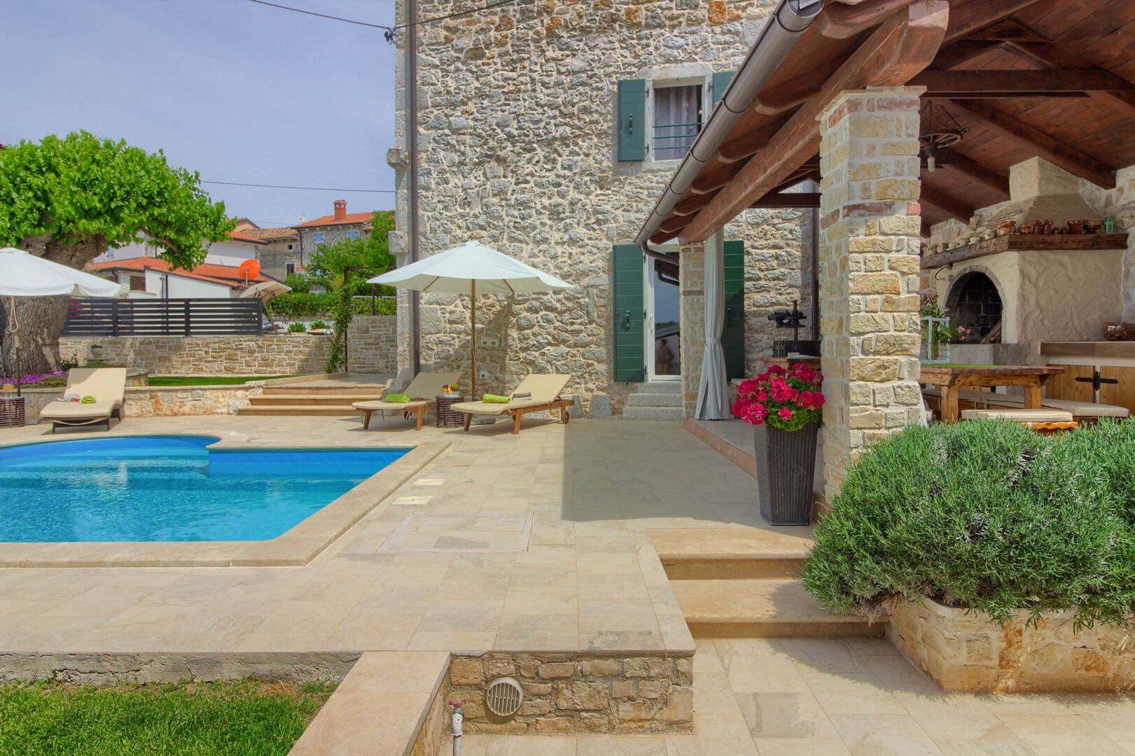 A stone building with a swimming pool, outdoor seating, and a barbecue area.