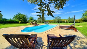 A swimming pool with lounge chairs and a tree in the foreground. - Apartment Mare2 (Istria - Banjole) (Banjole)