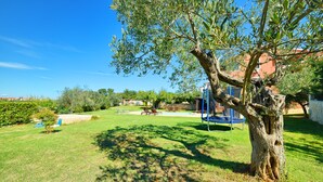 A backyard with a tree, a swing set, and a small pool. - Apartment Mare2 (Istria - Banjole) (Banjole)