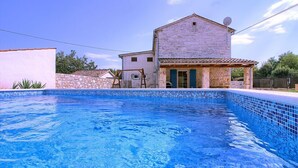 A swimming pool with a stone building in the background. - Villa Sasso (Istria - Rajki) (Rajki)