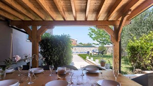 An outdoor wooden pergola with a table set for dining, overlooking a garden and a view of a building. - Villa Valbandon (Istria - Valbandon) (Valbandon)
