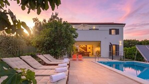 A modern building with a pool, lounge chairs, and a patio area. - Villa Medulin (Istria - Medulin) (Medulin)