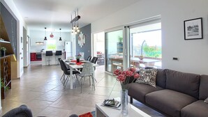 A modern living room with a sofa, coffee table, and a dining area with chairs and a table. - Villa Medulin (Istria - Medulin) (Medulin)