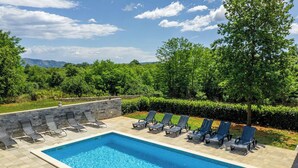 A rectangular swimming pool with a tiled deck, surrounded by lounge chairs and a stone wall. - Villa Eden (Istria - Labin) (Labin)